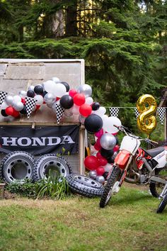 a motorcycle parked in front of a wooden box with balloons on it's back