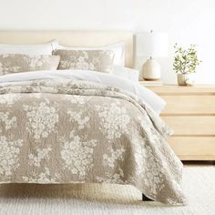 a bed with a white comforter and pillows on top of it next to a dresser