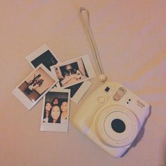 a polaroid camera sitting on top of a bed next to pictures and a chain