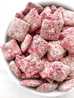 a white bowl filled with red and white sprinkled sugar cubes on top of a marble counter