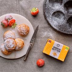 powdered sugar covered pastries and strawberries on a plate next to a pastry maker