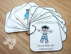 four cards with an astronaut on them sitting on a wooden table next to a pair of scissors