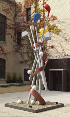 a sculpture in front of a building with golf balls and tees on top of it