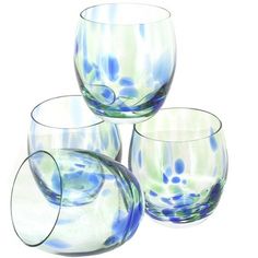 three glasses are sitting next to each other on a white surface with blue and green swirls