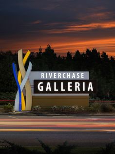 the river chase gallery sign is lit up at night, with trees in the background