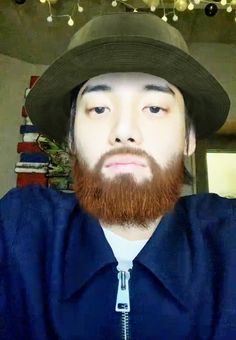 a man with a red beard wearing a hat and blue shirt looking at the camera