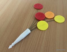 four different colored buttons sitting on top of a wooden table next to a white marker