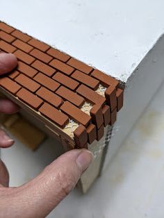 a hand is holding a piece of brick