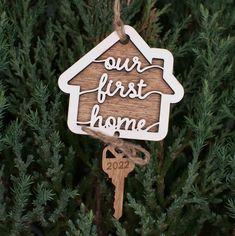 a wooden ornament hanging from a tree with the words our first home on it