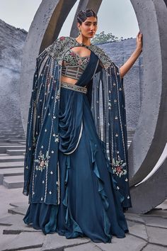 Blue panelled cape with floral embroidery. Paired with attached cancan lehenga and embroidered padded corset blouse.
Components: 3
Pattern: Embroidered
Type Of Work: Floral
Neckline: V neck
Sleeve Type: Cape sleeves
Fabric: Georgette, viscose satin organza  
Color: Blue
Other Details: 
Tassel detailing
Criss cross detailing
Lehenga length: 45
Occasion: Wedding - Aza Fashions