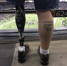 a person with a tattoo on their leg stands next to a parking meter in front of a football stadium