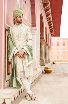 a man in a white and green outfit leaning against a wall