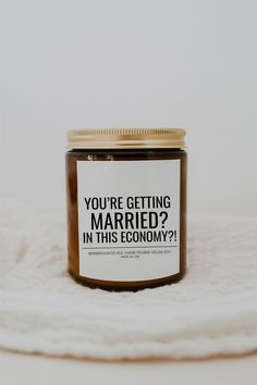 a jar of peanut butter sitting on top of a white blanket with the words you're getting married in this economy