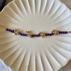 a white plate topped with a purple beaded necklace