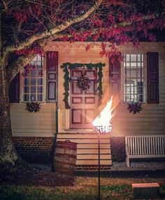 a fire is lit in front of a house with wreaths on the door and windows