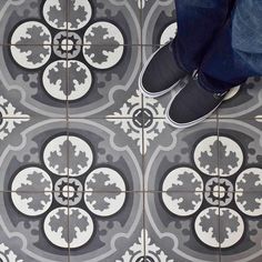 a person standing on a tiled floor with their feet propped up against the tile in front of them