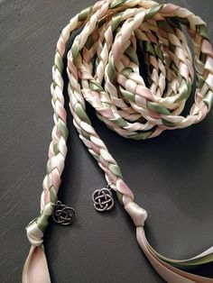 a white and green braided lanyard next to a pair of earrings on a table