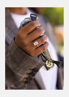 a person holding a cell phone and wearing a ring on their finger with a cross in the middle