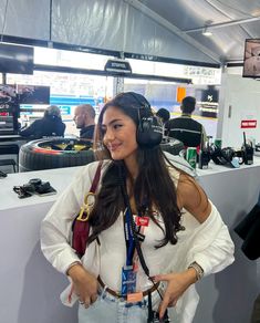 a woman with headphones on standing in front of a booth at an electronics store