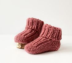 a pair of pink knitted baby booties sitting on top of a white surface