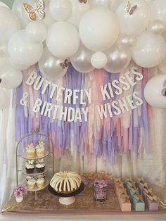 a dessert table with cake, cupcakes and balloons