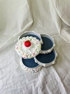 two cakes with sprinkles and a red apple in the middle on a white sheet