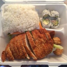 a plastic container filled with rice, meat and veggies next to sushi