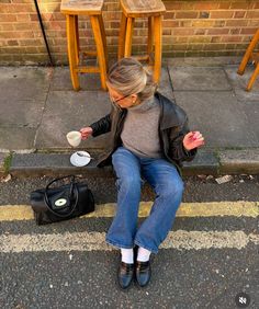 a woman is sitting on the curb eating