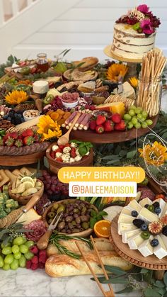 a table topped with lots of different types of cheeses and fruit on top of wooden trays