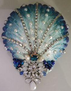 a blue brooch with pearls and crystals on it