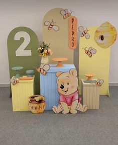 there is a teddy bear sitting in front of some honey pots and other decorations on the floor