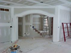 an unfinished room with white walls and ladders on the floor in front of it