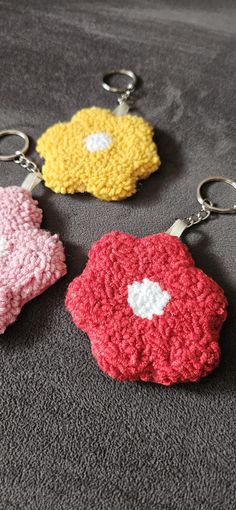 three crocheted keychains with hearts on them sitting on a gray surface