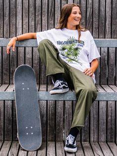 a woman sitting on a bench holding a skateboard