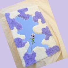 a purple and white rug with a flower on the ground in front of blue sky