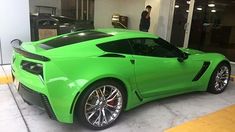 a green sports car is parked in front of a man standing next to the door