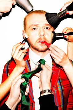 a man getting his tie put on by several other people with scissors and hairdryers