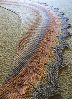 a close up of a knitted object on the ground with water and sand in the background