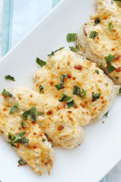 three pieces of chicken covered in cheese and herbs on a white plate with the words, parmesan crusted chicken