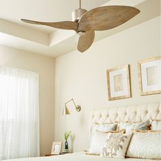 a bedroom with a bed, ceiling fan and pictures on the wall in front of it