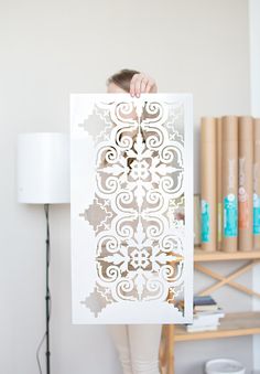 a woman holding up a cut out piece of paper with an intricate design on it