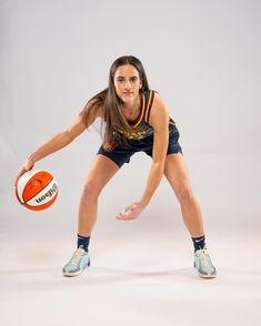 a woman holding an orange and white ball in her right hand while posing for the camera