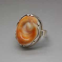 A lovely hallmarked silver ring with a polished curvy sea shell of vivid orange color. An unusual artisan handcrafted statement jewelry item from circa 1970's. The ring will be shipped in a gift box. Ring size: diameter 16.1 mm / US size: 5 1/2 / UK size: L / European - 51 3/4 Ring face measures almost 1 Inch tall (2.4 cm) - it is a true statement ring! Weight: 7.6 grams Hallmarked with a Dutch ZII hallmark for 835 continental silver Excellent vintage condition. The standard shipping for this it Unique Orange Ring Jewelry, Handmade Vintage Orange Rings, Orange Vintage Ring Jewelry, Vintage Handmade Orange Rings, Vintage Orange Ring Jewelry, Unique Oval Orange Jewelry, Orange Sterling Silver Ring, Orange Hand-strung Multi-strand Jewelry, Orange Sterling Silver Ring With Polished Finish