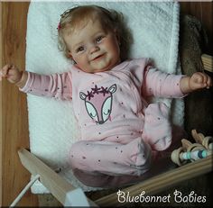 a baby laying on top of a blanket next to a wooden crib with toys