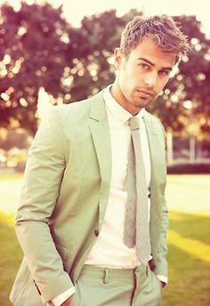 a man wearing a suit and tie standing in the grass