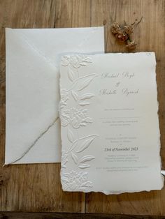 the wedding stationery is laid out on a wooden table