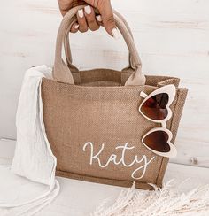 a person holding a tan bag with sunglasses on it and the word kathy written in white