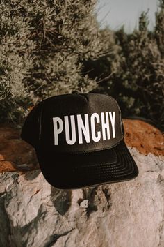 "punchy" trucker hat. color black with white vinyl Black Trucker Hat With Letter Print And Flat Bill, Black 5-panel Trucker Hat With Letter Print, Trendy Black Flat Bill Trucker Hat, Black 5-panel Snapback Hat With Letter Print, Black Letter Print Snapback Trucker Hat, Black Snapback Trucker Hat With Letter Print, Trendy Black Snapback Trucker Hat, Trendy Black Trucker Hat With Letter Print, Trendy Black 5-panel Snapback Hat