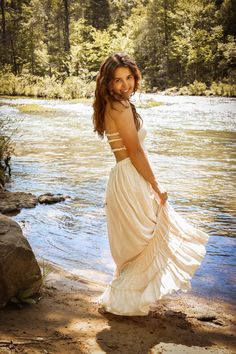 a woman in a white dress standing by the water