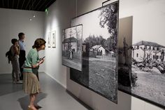 people looking at black and white photographs on display